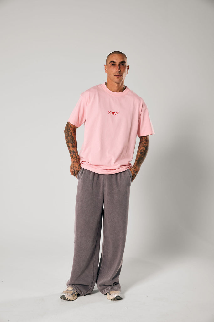 Person wearing a pink t-shirt and gray pants on a white background